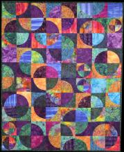 A colourful quilt made of patterned, multi-colour circles.