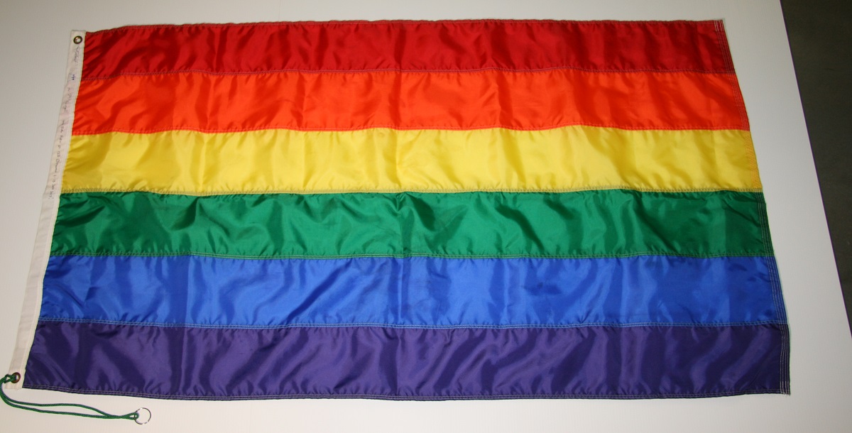 A rainbow Pride flag laid flat on a white table.