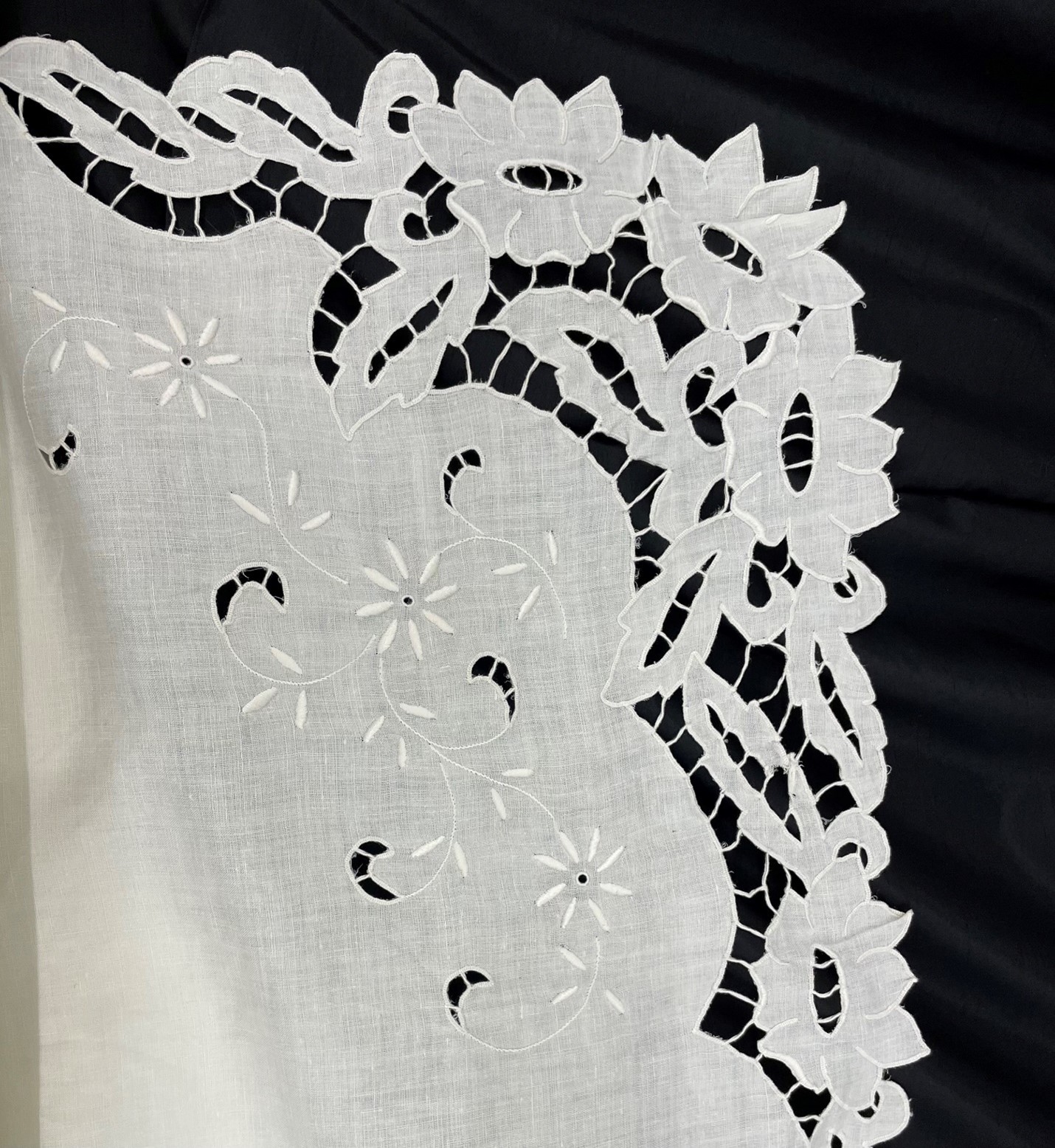 A close up of white lacey fabric on a black background
