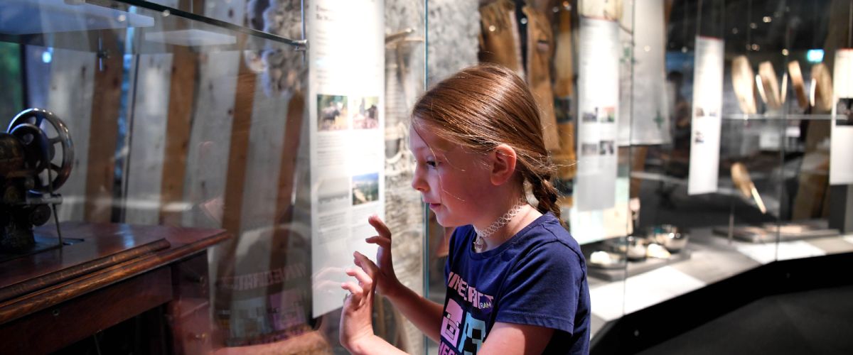 a young girl looks in a display case in the Human History Hall