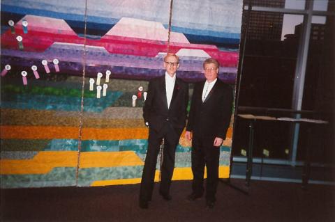 Two men in suits stand beside the Living Quilt