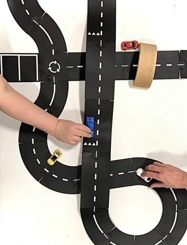 Driving toy cars on a crafted road.