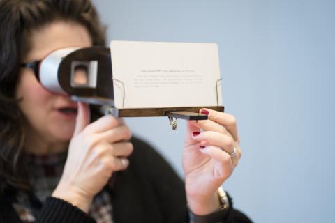 A Museum patron peers through an antique stereoscope. 