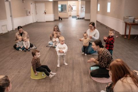 Toddlers and their parents participate in a circle activity.