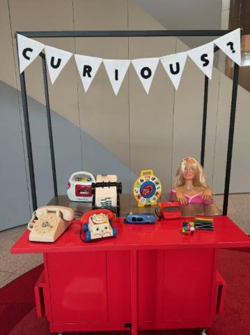 A table with old toys and a sign above that says curious.