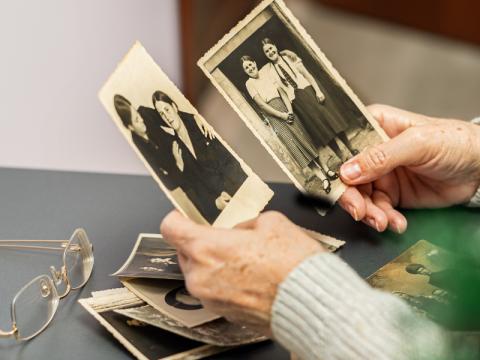An old pair of hands holding old black and white photographs.