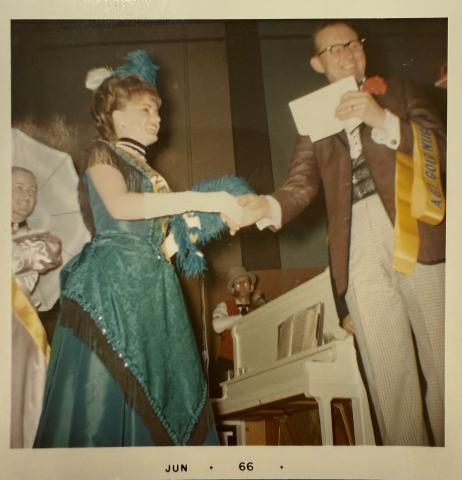 Simone Bessette being awarded the title of "Gold Nugget Princess" at the 1966 Edmonton Klondike Days. She is wearing the elaborate dark green dress and head piece.