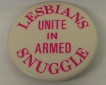 A white pin with the words "Lesbians unite in armed snuggle"