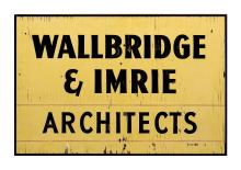 A historical sign. The sign is yellow with distressing from age. It says Wallbridge & Imrie Architects.