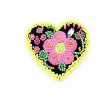 A beautiful beaded heart pin. The heart is black with yellow beads around the edge and a large pink flower in the centre.