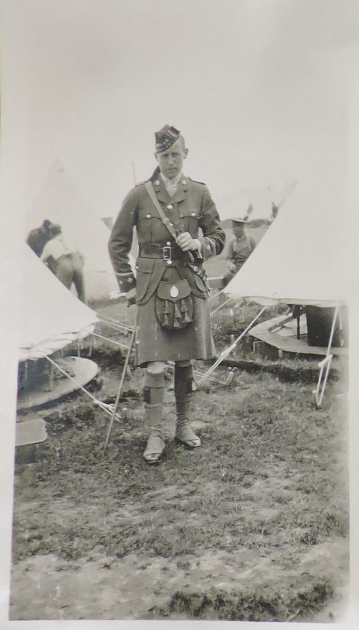 Solider William Frame in his military uniform poses in front of tents at Camp Sarcee, July 1916. 